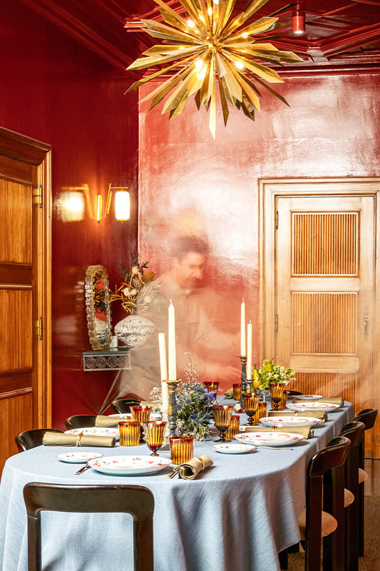 Dining table set for a meal with candles and decorative items in a warm, softly lit room.