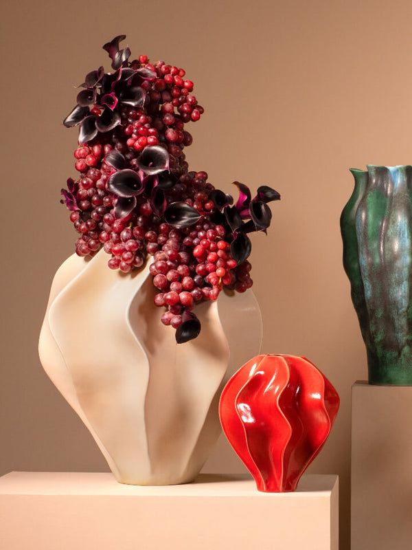 Collection of decorative vases with flowers and fruits on a beige background