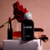 black bell shaped glass bottle with round crackle top styled with a moody red background and rose 
